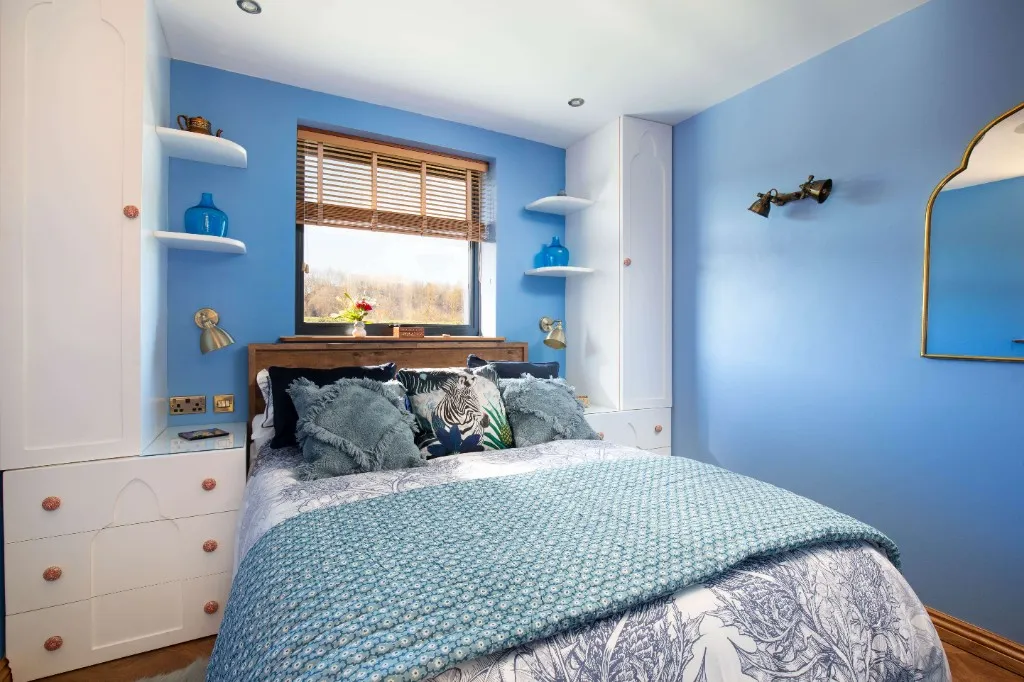 Double bedroom with blue walls and botanical bedding at an Enchanted Lodge, Woodhill Weddings, Faversham, Kent