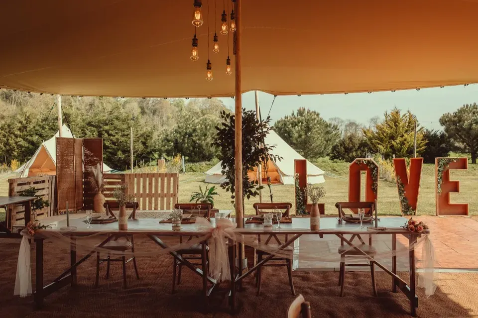 Wedding tables dressed under the Bedouin stretch tent with LOVE letters and countryside views at Woodhill Weddings, Faversham, Kent